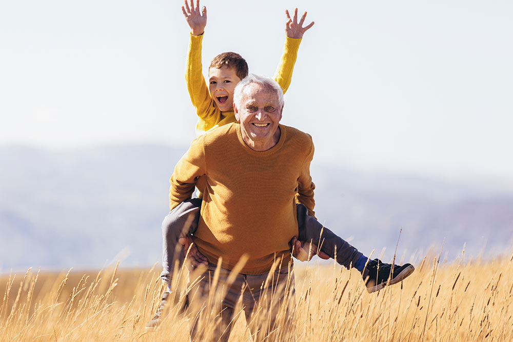 Grandson piggyback with his grandfather in autumn